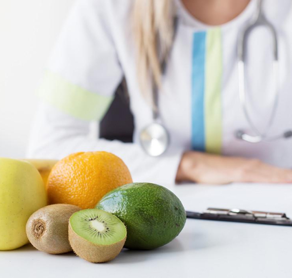 Una mujer con frutas en la mesa dando un servicion de nutricion.